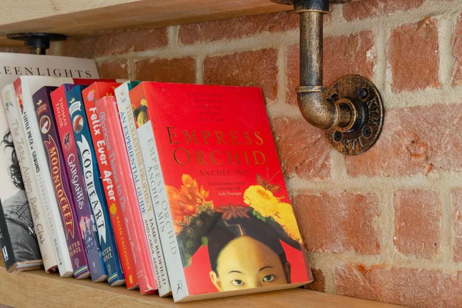 A few books for you to enjoy laid out on a shelf fitted to the exposed brick work
